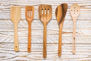 Set of five different wooden cooking utensils on a rustic wooden background