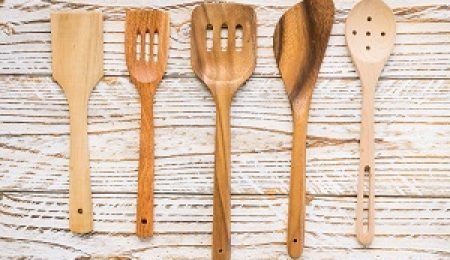 Set of five different wooden cooking utensils on a rustic wooden background